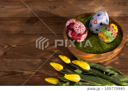 An aerial view of a bowl with large colorful Easter eggs on a background of planks. An aerial view of a bowl with large colorful Easter eggs on a background of planks. 100770980