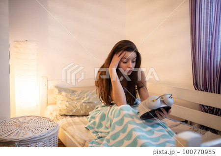 The teenage girl doesn't like her alarm clock. 100770985