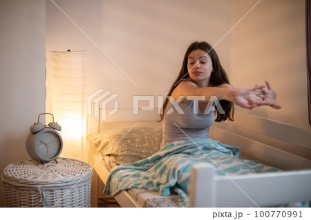 A young woman stretches after a long sleep. A young woman stretches after a long sleep. 100770991