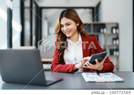 Beautiful young teen asian businesswoman using computer laptop and calculator for calculate with planning working on financial document, tax, exchange, accounting and Financial advisor. Beautiful young teen asian businesswoman using computer laptop and calculator for calculate with planning working on financial document, tax, exchange, accounting and Financial advisor. 100772569