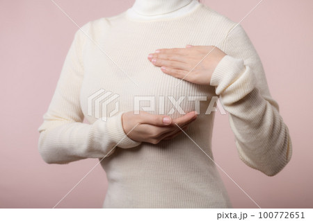 Woman hands checking lumps on her breast for signs of breast cancer on pink background. Healthcare world health day concept. Woman hands checking lumps on her breast for signs of breast cancer on pink background. Healthcare world health day concept. 100772651