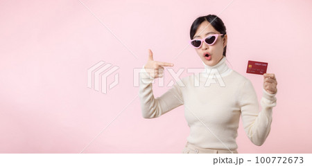 Fascinating fun joyful young woman of Asian ethnicity 20s years old with wear sunglasses wears white shirt hold in hand credit bank card isolated on plain pastel light pink background studio portrait. Fascinating fun joyful young woman of Asian ethnicity 20s years old with wear sunglasses wears white shirt hold in hand credit bank card isolated on plain pastel light pink background studio portrait. 100772673