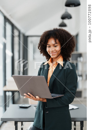Beautiful young teen American African holding computer laptop with planning working on financial document, tax, exchange, accounting and Financial advisor. 100772898