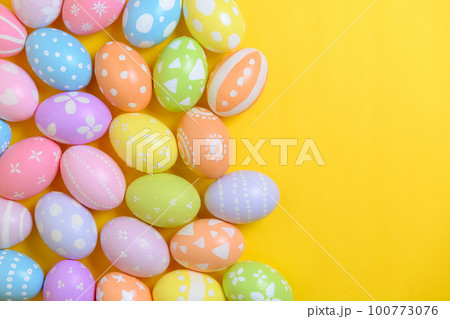 Happy easter holiday celebration concept. Group of painted colourful eggs decoration on a yellow background. Seasonal religion tradition design. Top view, flat lay, copy space. 100773076