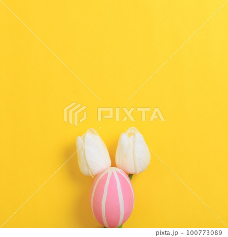 Happy Easter holiday greeting card design concept. Colorful Easter Eggs and spring flowers on yellow background. Flat lay, top view, copy space. 100773089