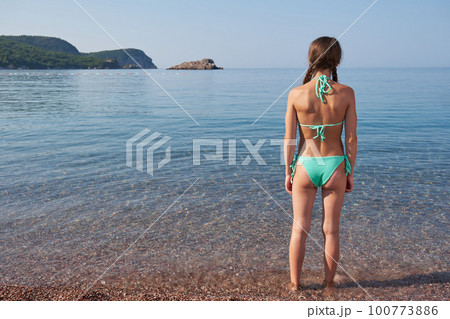 Teenage girl in bathing suit enters the clear transparent sea