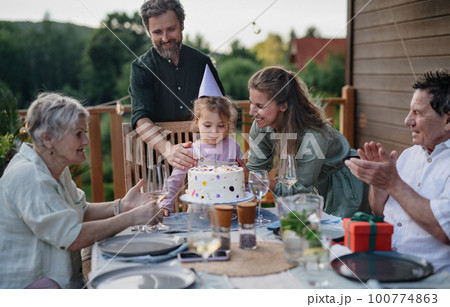 Multi generation family celebrating birthday and have garden party outside in the backyard on patio. Multi generation family celebrating birthday and have garden party outside in the backyard on patio. 100774863