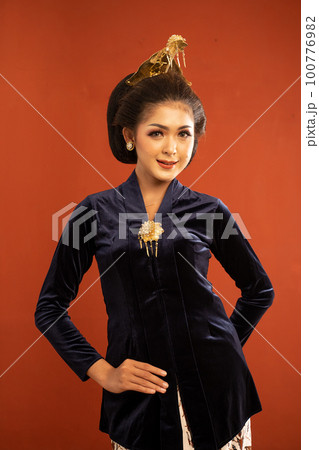 woman in kebaya standing put her hand behind and touch her kebaya 100776982