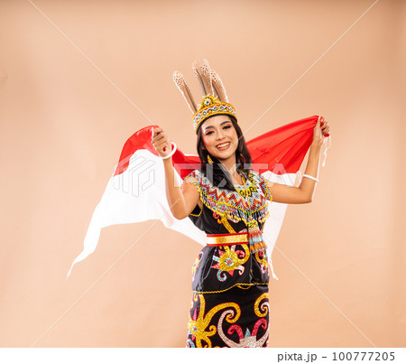 woman in traditional clothes of dayak tribe grab and waving the flag woman in traditional clothes of dayak tribe grab and waving the flag 100777205