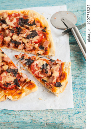 homemade pizza with salami, tomatoes and herbs 100778322