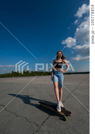 Young caucasian woman riding a longboard outdoors.  100778859