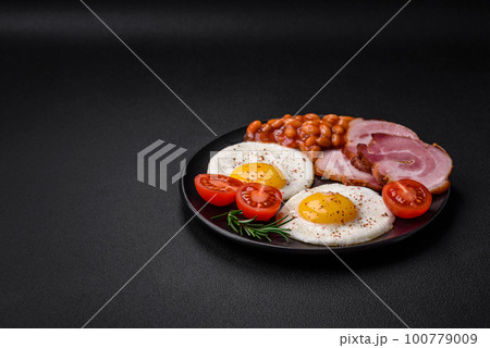 Delicious nutritious English breakfast with fried eggs and tomatoes Delicious nutritious English breakfast with fried eggs and tomatoes 100779009