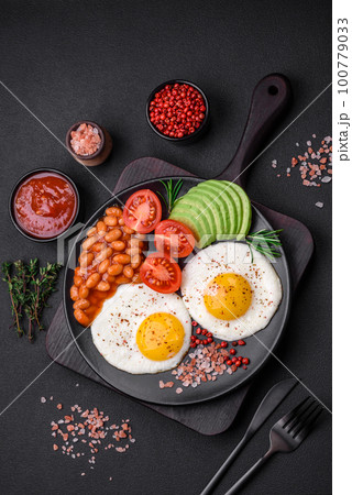 Delicious nutritious English breakfast with fried eggs, tomatoes and avocado 100779033