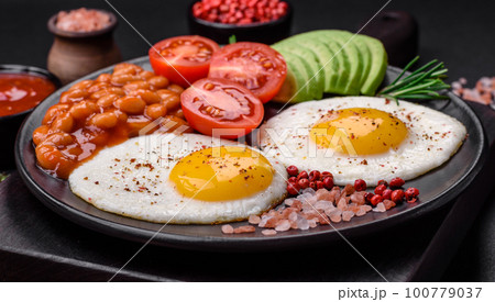 Delicious nutritious English breakfast with fried eggs, tomatoes and avocado 100779037