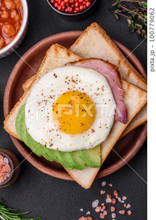 Delicious nutritious English breakfast with fried eggs, tomatoes and avocado 100779062