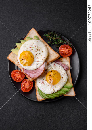 Delicious nutritious English breakfast with fried eggs, tomatoes and avocado 100779068