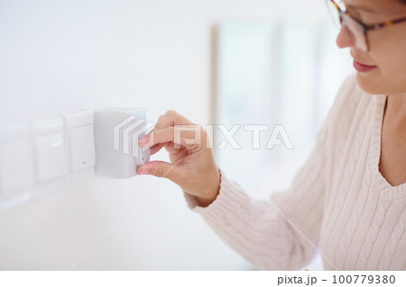Woman adjusting thermostat. Central heating. 100779380