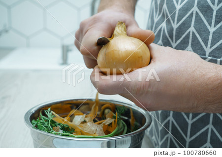 Male hands peeling by knife yellow onion over bowl of vegetable peelings closeup. Healthy nutrition, vegetables. Male hands peeling by knife yellow onion over bowl of vegetable peelings closeup. Healthy nutrition, vegetables. 100780660