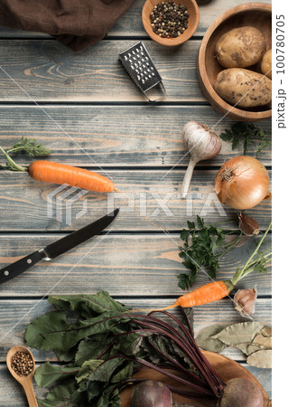 Knife for peeling carrots, flat lay. Mix of raw fresh organic vegetables on wooden table. Zero waste, eco concept. 100780705