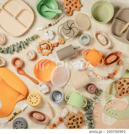 Pastel silicone collection of tableware, cutlery, bibs, accessories, wooden toys for children on white cloth background. Pastel silicone collection of tableware, cutlery, bibs, accessories, wooden toys for children on white cloth background. 100780901