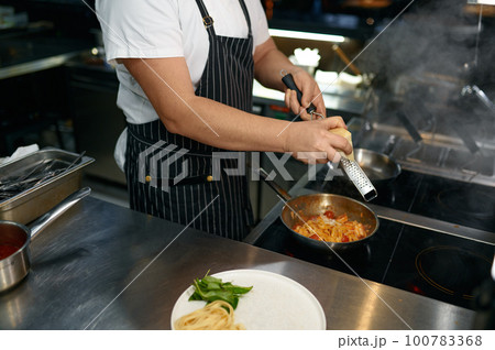 Chef grating cheese on pasta, closeup view of hands Chef grating cheese on pasta, closeup view of hands 100783368
