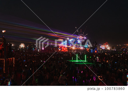 People walking towards sunset at a festival in the desert. Beautiful music festival in a desert. 100783860
