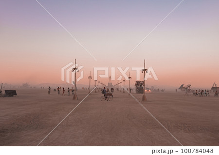 People walking towards sunset at a festival in the desert. Beautiful music festival in a desert at the Burning Man festival. People walking towards sunset at a festival in the desert. Beautiful music festival in a desert at the Burning Man festival. 100784048