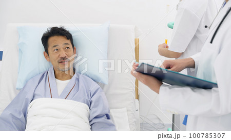 病床で医師と話す入院患者 100785307