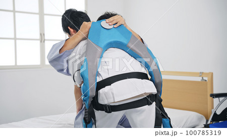 パワーアシストスーツをつけて患者を抱える看護師 移乗介助機器 パワーアシストスーツをつけて患者を抱える看護師 移乗介助機器 100785319