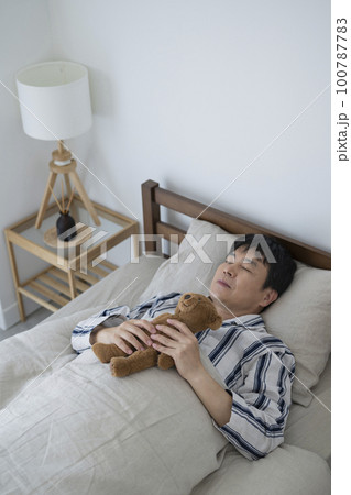 テディベアを抱いて眠る50代男性,朝 テディベアを抱いて眠る50代男性,朝 100787783