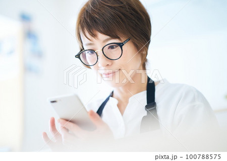 メガネをかけてスマートフォンを操作する女性 メガネをかけてスマートフォンを操作する女性 100788575