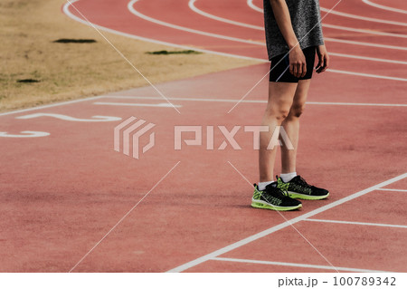 陸上競技場のトラックでスタートラインに立つ男性ランナー 100789342
