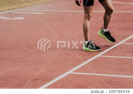 陸上競技場のトラックでスタートラインに立つランナー 100789349