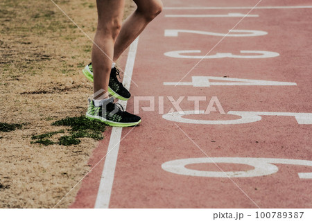 陸上競技場のトラックに立つスタート前のランナー 100789387