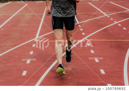 陸上競技場のトラックでスタートダッシュする男性ランナー 100789692