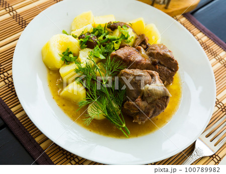 Tasty lamb with mushrooms and potatoes served at plate with greens 100789982