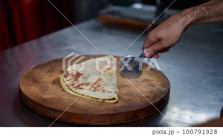 Cutting a folded Tortilla with a roti cutter by the chef in a restaurant. 100791928