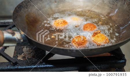 Deep frying falafel balls in wok, hot cooking oils bubbling and falafel balls turned golden brown color 100791935
