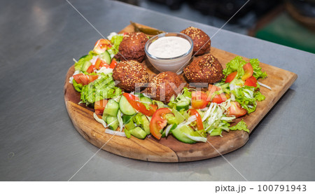 Falafel plate with vegetables salad and sauce on the kitchen table close up. Falafel plate with vegetables salad and sauce on the kitchen table close up. 100791943