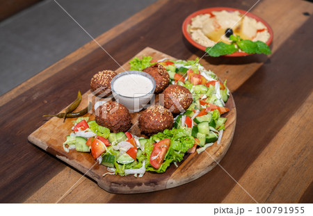 Falafel plate with vegetables salad and sauce on the table. 100791955