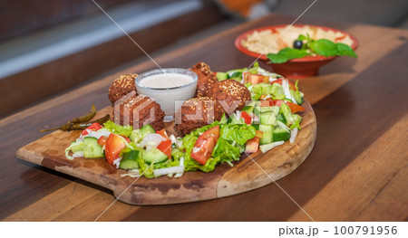 Falafel plate with vegetables salad and sauce on the table. Falafel plate with vegetables salad and sauce on the table. 100791956