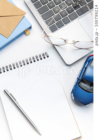 Modern white office desk table with laptop, notebook, toy car and other supplies. Modern white office desk table with laptop, notebook, toy car and other supplies. 100799214
