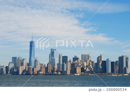 Gorgeous view of the Manhattan skyline with the Freedom Tower over a calm sea on a sunny day Gorgeous view of the Manhattan skyline with the Freedom Tower over a calm sea on a sunny day 100800534