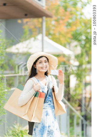 紙袋を持ってクレジットカードでショッピングを楽しむ若い女性 久屋大通公園にて 100803393