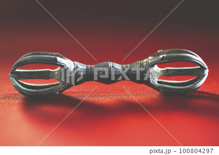 古い仏教 密教法具の金剛杵（五鈷杵）赤い和生地（ちりめん生地）に置に置いて撮影した五鈷杵 100804297