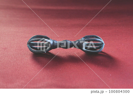 古い仏教 密教法具の金剛杵（五鈷杵）赤い和生地（ちりめん生地）に置に置いて撮影した五鈷杵 100804300