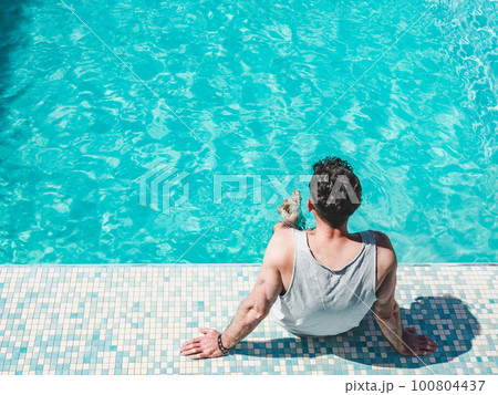 Handsome man sitting near the swimming pool Handsome man sitting near the swimming pool 100804437