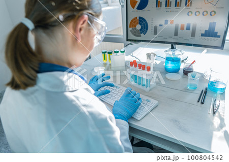 A female researcher sits at a workplace in a laboratory, behind a personal computer monitor. A female researcher sits at a workplace in a laboratory, behind a personal computer monitor. 100804542