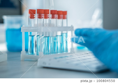A female researcher sits at a workplace in a laboratory, behind a personal computer monitor.  100804550