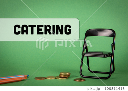 Catering concept. Miniature chair, change and pencils on a green background Catering concept. Miniature chair, change and pencils on a green background 100811413